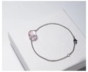 Detail van roze kristallen armband met zilveren ketting op wit sieradendoosje