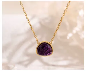 Macro shot of geometric gold triangle necklace with deep purple swirl pattern stone