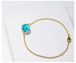 Macro-opname van de vergulde kettingarmband met vierkante blauwe kristal en karabijnsluiting