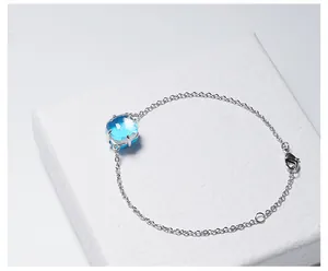 Detail van de blauwe kristallen armband met zilveren ketting en sluiting op een wit doosje