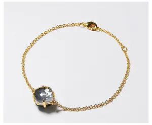 Detailopname van een gouden armband met een groot vierkant geslepen kristal in een klauwzetting