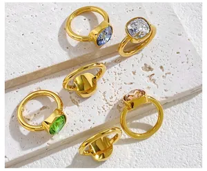 Close-up of square cut crystal rings in vibrant colors on a natural stone base