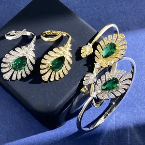 Detailansicht goldener und silberner Federringe und Armreifen mit grünen Edelsteinen