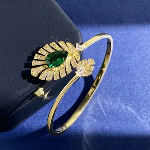 Detailansicht eines smaragdgrünen Edelstein-Armbands mit goldenen Feder-Diamant-Akzenten