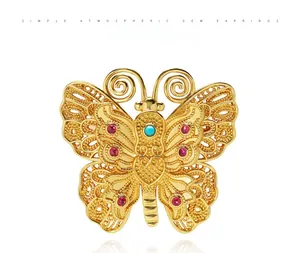 Vue macro de la broche papillon vintage avec pierres rouges et détails filigranes