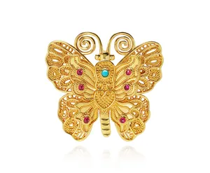 Détail macro d'une broche papillon dorée avec filigrane et pierres précieuses colorées