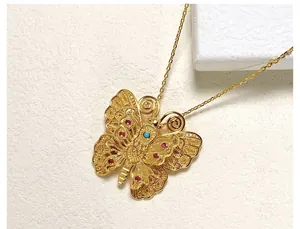 Vue macro du pendentif papillon doré avec détails filigranes et gemmes colorées