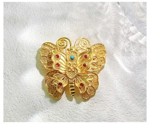 Détail de la broche papillon en or vintage avec filigrane et pierres précieuses