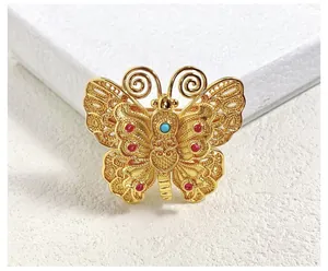 Gros plan sur la broche papillon vintage avec filigrane d'or et pierres précieuses