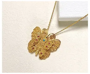 Détail d'une broche papillon dorée vintage avec gemmes rouges et bleues sur pierre