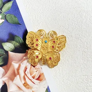 Broche papillon vintage dorée ornée de cristaux rouges et d'une pierre bleue centrale