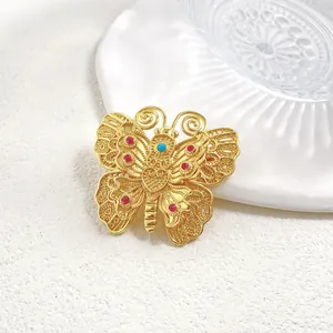 Broche papillon vintage dorée avec ailes en filigrane et incrustations de gemmes
