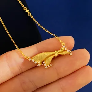 Detailed macro view of gold ribbon bow necklace featuring brushed texture and micro diamonds