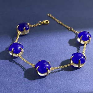 Golden bracelet with five deep blue square gemstones and lobster clasp on dark background