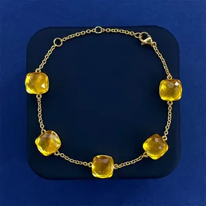 Macro view of five-flower gold bracelet featuring faceted yellow crystal gems on blue background