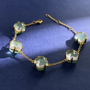 Close-up of five faceted green crystals on a gold chain bracelet with lobster clasp