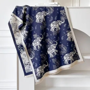 Close-up of deep blue cashmere scarf featuring paisley elephant patterns and fringed edges