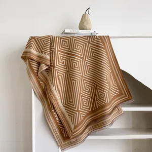 Close-up of thick brown cashmere-like scarf with Greek key pattern and soft fringes