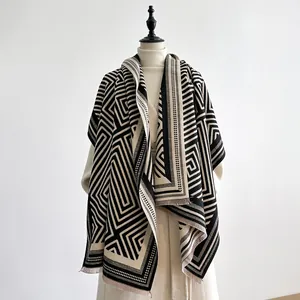 Detail of geometric pattern and fringe trim on a thick black and white cashmere scarf