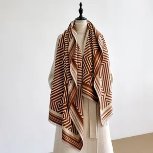 Detail of soft cashmere feel scarf with geometric pattern and fringe edges in brown