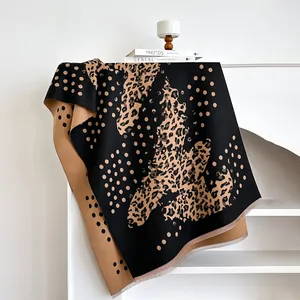 Thick winter leopard and polka dot scarf with fringes on a white shelf for home display
