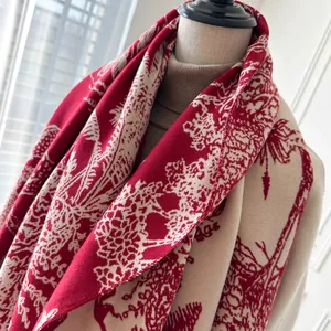 Detailed close-up of a thick cashmere-feel shawl with red reindeer and forest patterns