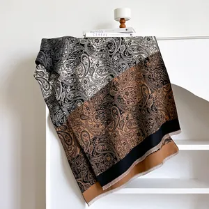 Close-up of black and beige paisley cashmere-like scarf with delicate fringe edges
