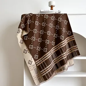 Detail of double-sided knit shawl with clover patterns and soft tassels in brown and cream