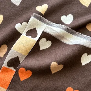 Detail of colorful heart patterns and fringe tassels on a thick brown cashmere-like scarf