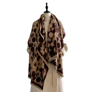 Sciarpa oversize in cashmere a pois marrone e beige con frange su un cappotto bianco