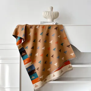 Detail of soft brown cashmere shawl with colorful bee embroidery and striped tassel edges