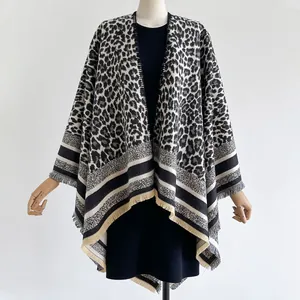 Detail of leopard print knit shawl featuring fine fringe edges and striped patchwork hem