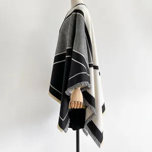 Detail of color-block knit shawl with tassels in black, white, and grey geometric patterns