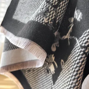 Detailed close-up of woven scarf featuring floral bird patterns and delicate fringe trim