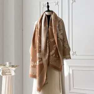 Detail of floral bird print scarf with fringe edges on a mannequin with beige coat