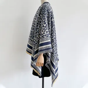 Detail of navy and beige leopard print shawl with striped hem and tassels on a mannequin