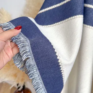 Detailed close-up of navy and cream striped knit scarf with elegant fringe edges