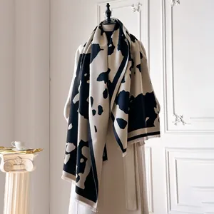 Détail d'un châle épais à motif vache avec franges sur un manteau beige élégant