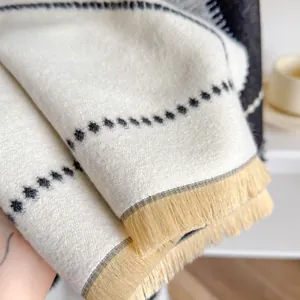 Folded cream cashmere-feel scarf with wavy black polka dots and soft yellow tassels