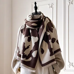 Détail d'une écharpe douce au toucher cachemire avec motif vache marron et franges