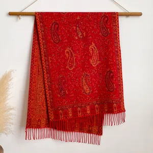 Dettaglio dello scialle paisley rosso con frange su asta di legno e decorazioni