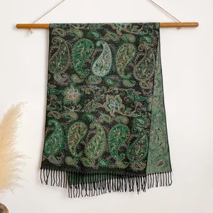 Λεπτομέρεια σκούρο πράσινο σάλι με σχέδιο paisley και κρόσσια κρεμασμένο σε ξύλινη βάση