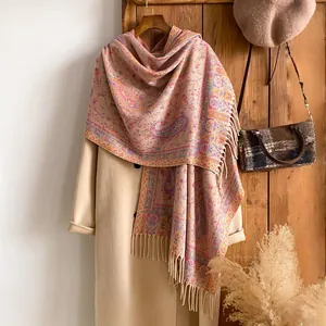 Dettaglio dello scialle paisley rosa con frange su un cappotto e sfondo in legno