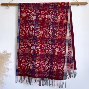 Écharpe rouge foncé à motif paisley rétro avec franges sur une barre en bois