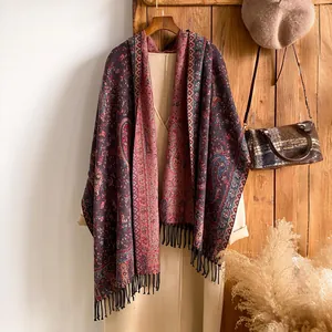 Dettaglio dello scialle vintage con motivo paisley, nappe nere e trama retrò