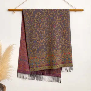 Detailed embroidery and tassel hem on ethnic floral scarf displayed on a wooden hanger