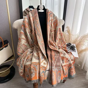 Détail du châle paisley vintage montrant la texture jacquard orange et les franges