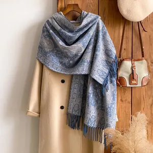 Dettaglio di scialle in lana blu con motivo paisley e frange su un cappotto autunnale