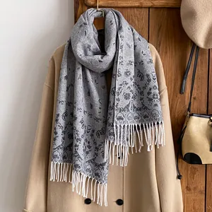 Detailed macro view of the grey floral jacquard scarf with decorative white tassels