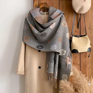 Detail of vintage floral jacquard cashmere feel scarf with fine tassel fringe on wool coat